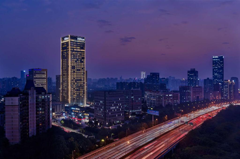 重庆重庆两江新区高科希尔顿酒店的高速公路上交通的城市在夜间亮起