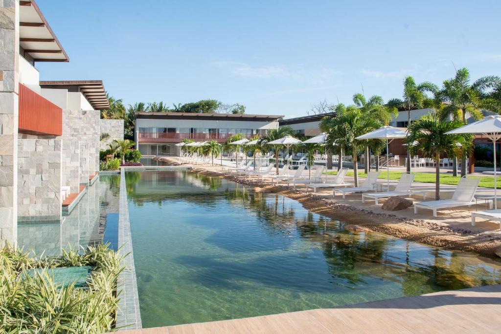 皮帕île de Pipa - Ma Plage Hotel的度假酒店的游泳池配有椅子和遮阳伞