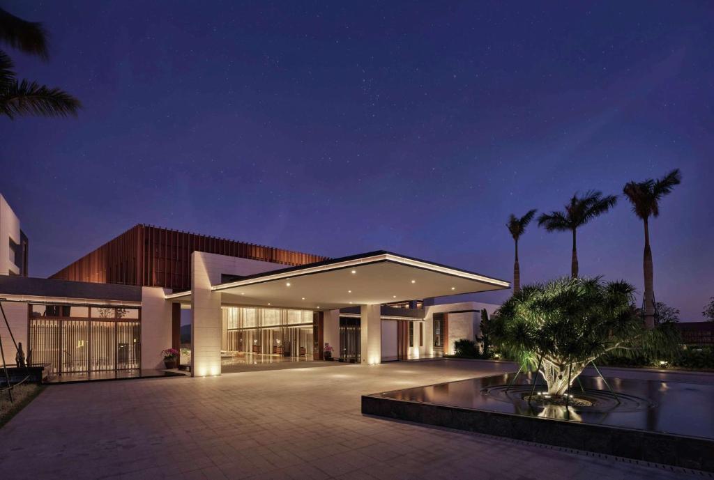 万宁海南兴隆希尔顿逸林滨湖度假酒店（网红泳池+天然温泉+免费亲子旅拍）的一座棕榈树环绕的大建筑