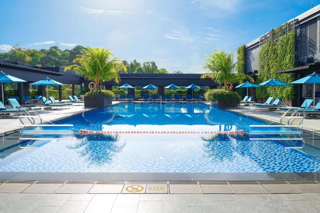 哥打京那巴鲁哥打京那巴鲁希尔顿酒店的一个带蓝伞和椅子的大型游泳池