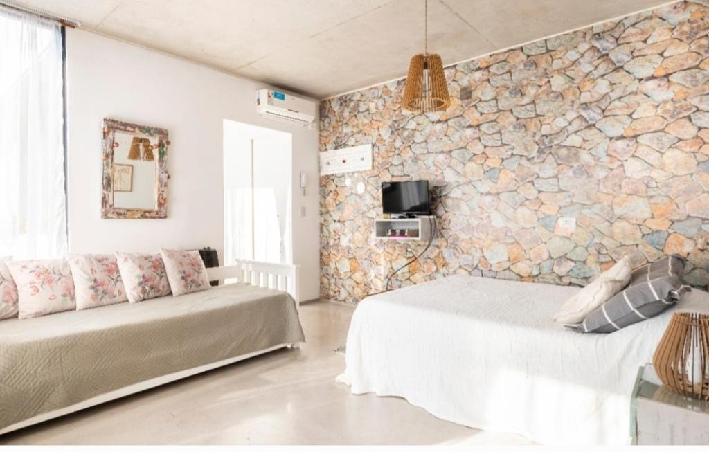 Remedios de EscaladaLuminoso y comfortable monoambienteA 25 minutos de Ezeiza的一间卧室设有两张床和石墙