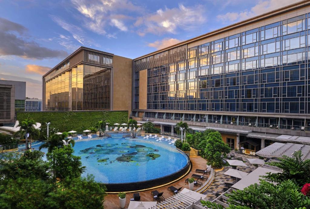 马尼拉Hilton Manila的一座大型建筑,前面设有一个大型游泳池