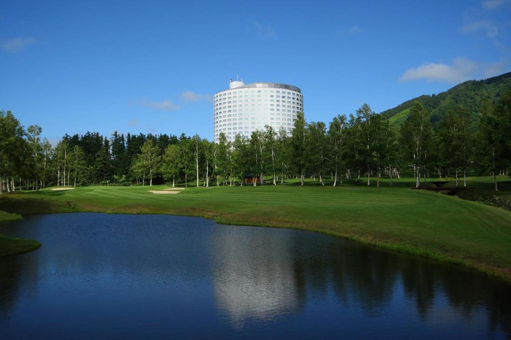 二世古北海道新雪谷希尔顿度假酒店的一座高尔夫球场,旁边是一座大楼,设有池塘