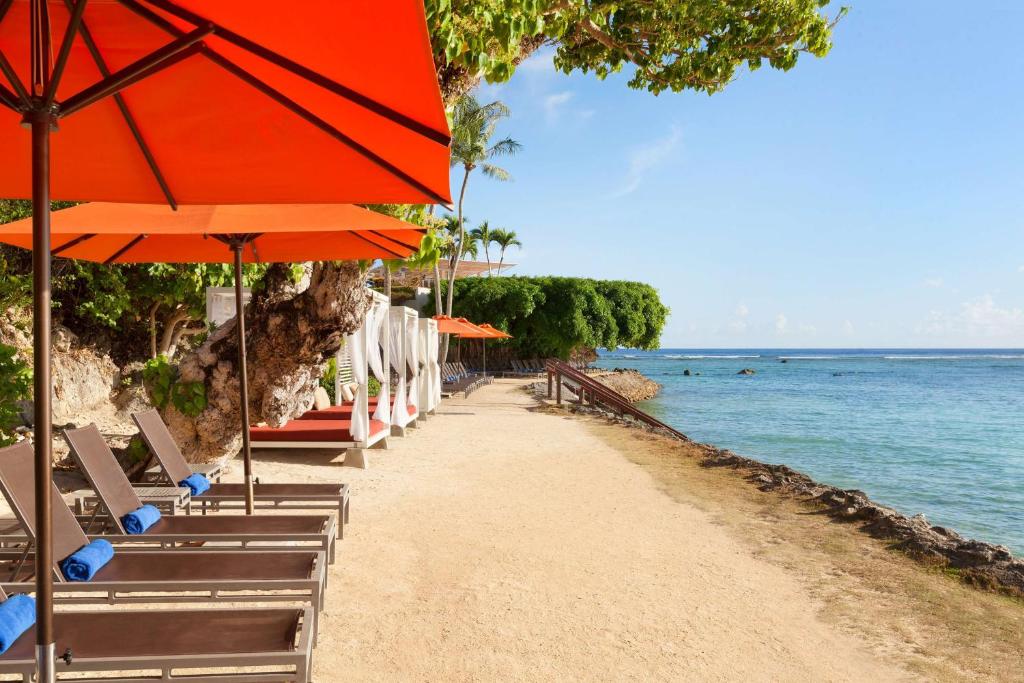 塔穆宁关岛希尔顿spa度假酒店的海滩上设有椅子和遮阳伞,还有大海