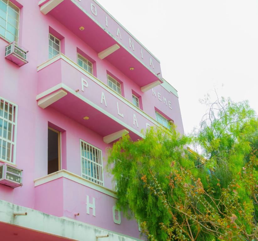 戈亚尼亚Goiânia Palace Hotel的粉红色的建筑,上面有标志