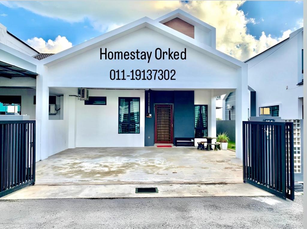 阿罗士打ORKED HOMESTAY的白色的房子,上面有书写家居的标志