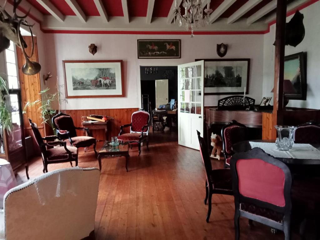 普佐日Domaine de Frély的客厅铺有木地板,配有椅子和桌子