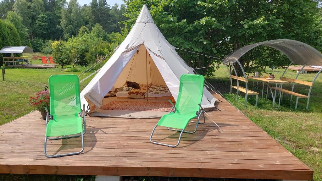 普里恩斯慕斯Glamping Fluffy Horns - Glempings Pūkainie Ragi的木制甲板上配有2把绿色椅子的帐篷