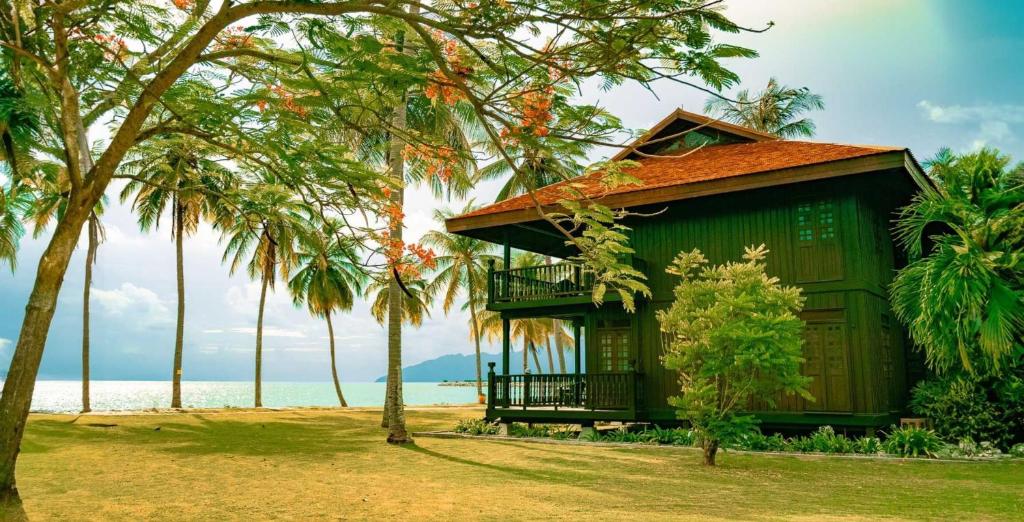 珍南海滩Pelangi Beach Resort & Spa, Langkawi的海滨绿色别墅,种有棕榈树