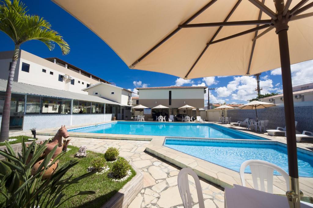 阿拉卡茹Hotel Rekinte的一座带遮阳伞的游泳池位于大楼旁
