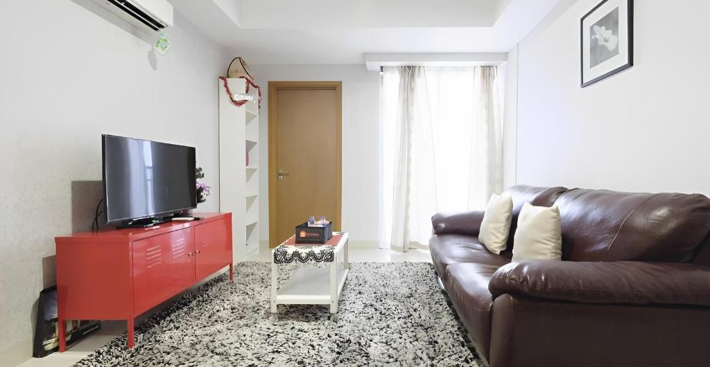 雅加达Cozy & Elegant The Mansion Jasmine Tower Capilano的客厅配有棕色真皮沙发和平面电视。