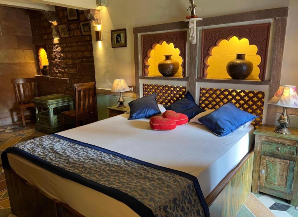 焦特布尔Banaji Heritage Haveli的一间卧室配有一张带蓝色和红色枕头的大床
