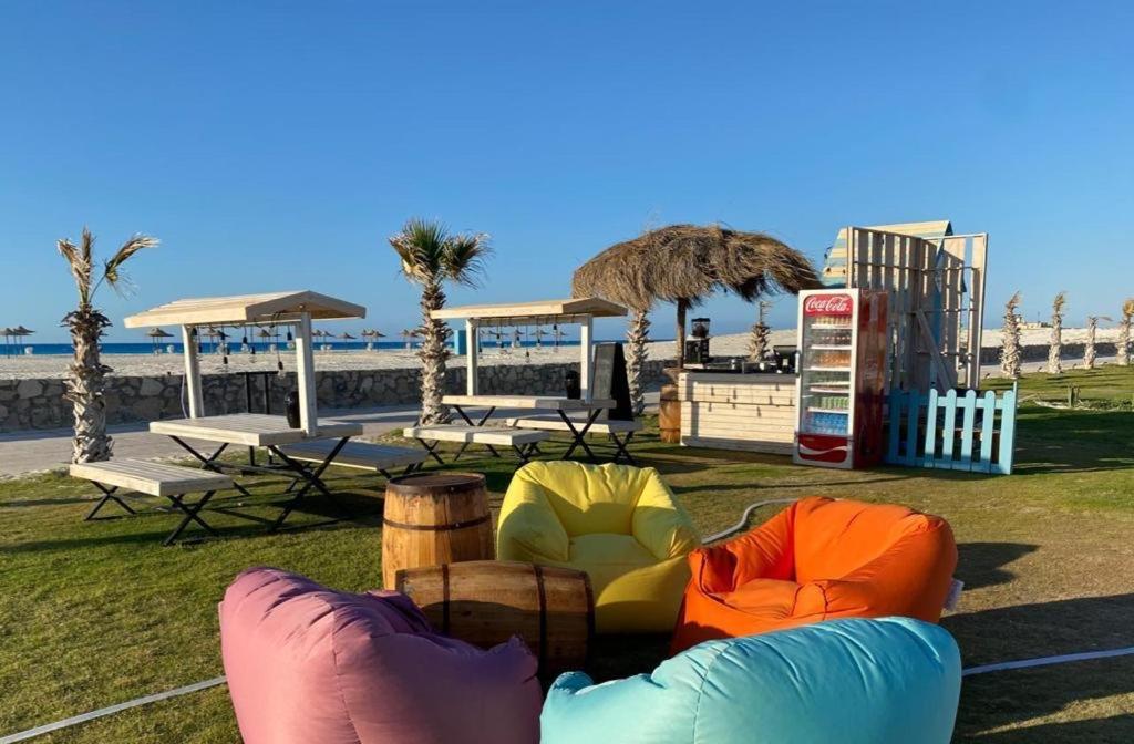 阿莱曼شاليه قرية قرطاج الساحل الشمالي的海滩上一座公园,公园里摆放着五颜六色的桌椅