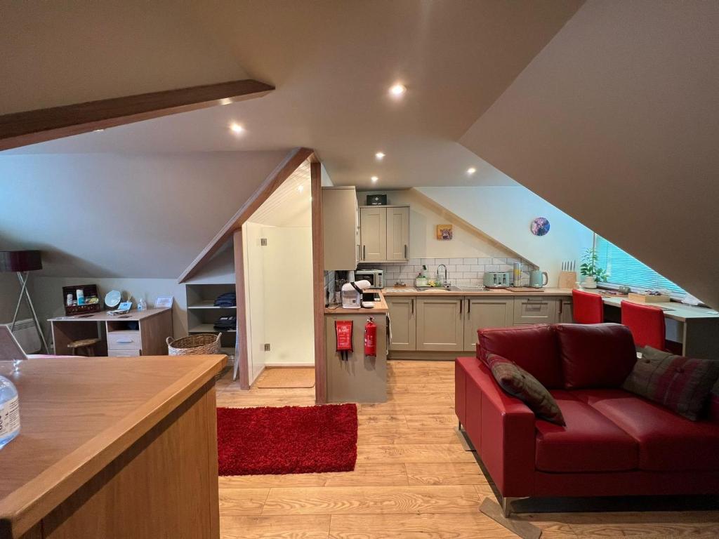 皮特洛赫里Inviting 1-Bed Studio in Pitlochry的一间带红色沙发的客厅和一间厨房