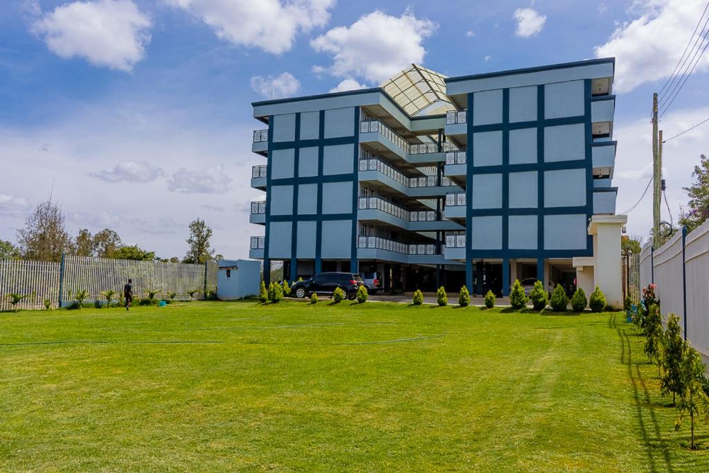 纳纽基Ebony Batian Nanyuki 1bedroom的一座大型蓝色建筑,设有大型草地庭院