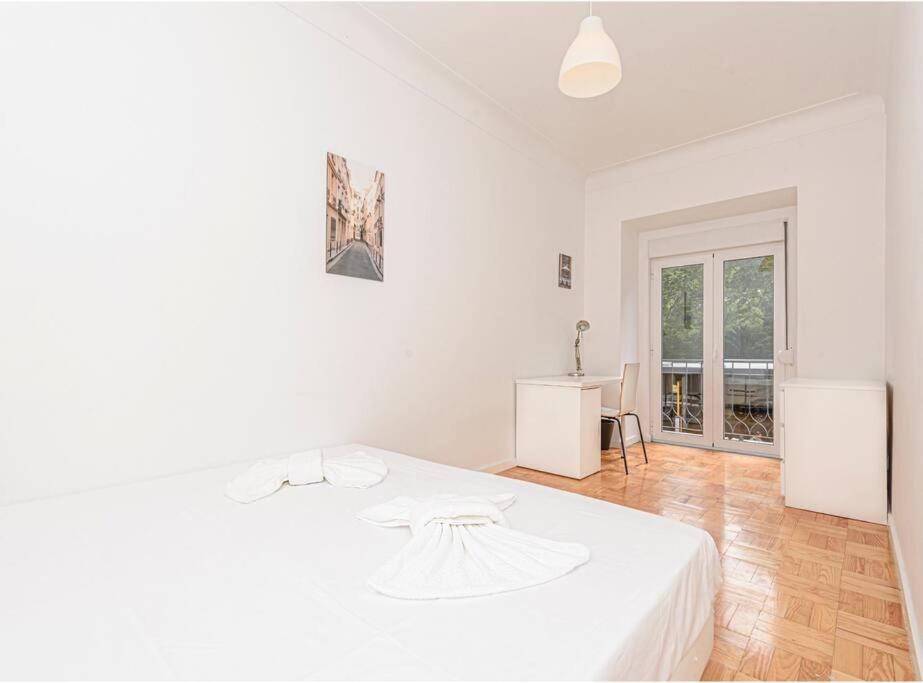 里斯本HOUZE_4 room apartment in Central Lisbon near Zoo的白色的卧室配有白色的床和一张桌子