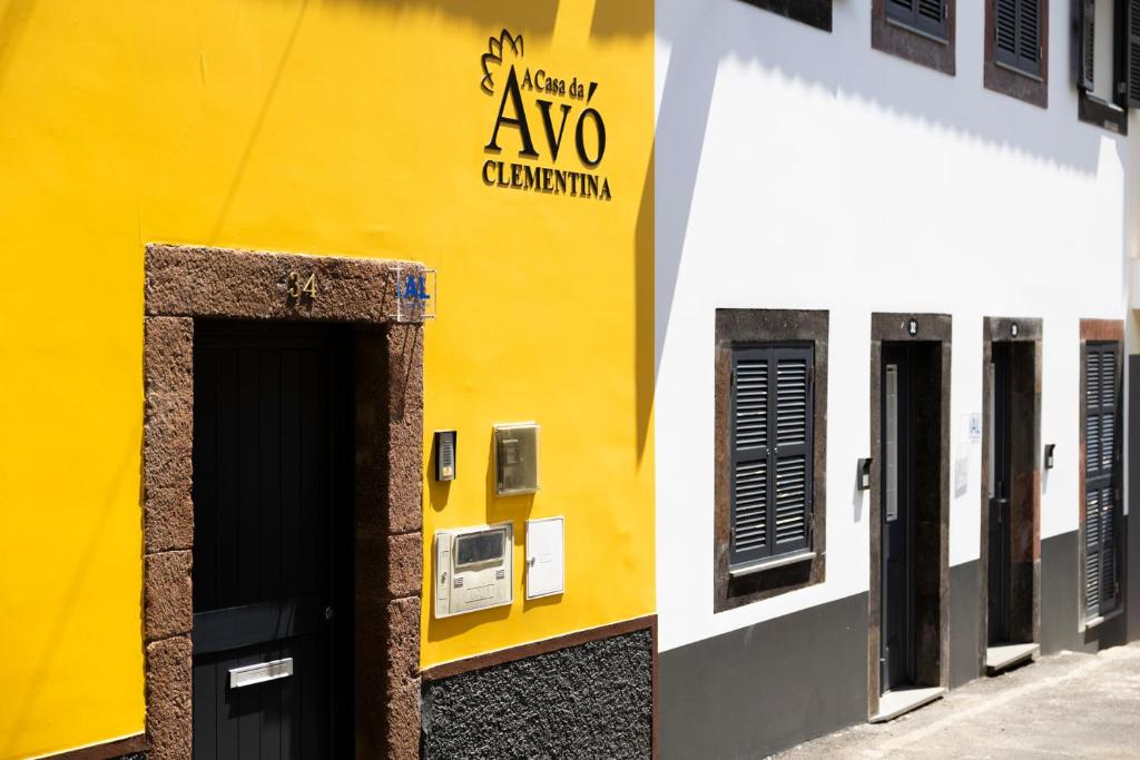 丰沙尔Casa Da Avo Clementina的黄色和白色的建筑,上面有标志
