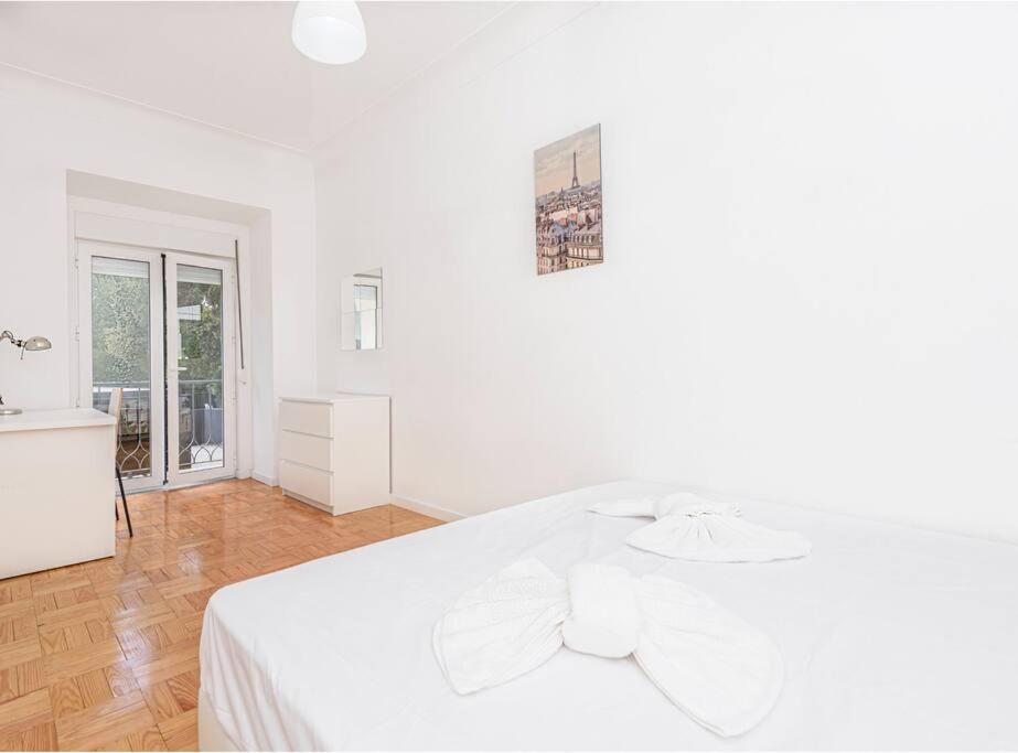 里斯本HOUZE_4 room flat in Central Lisbon near Zoo的白色卧室设有白色的床和木地板