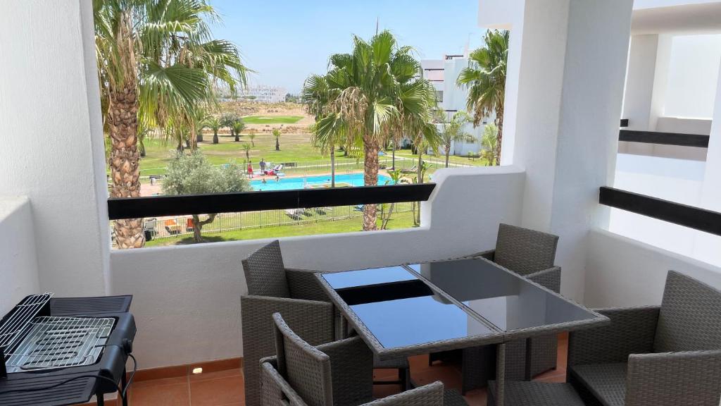 穆尔西亚Apartamento golf-resort murcia的阳台配有桌椅,享有游泳池的景致。