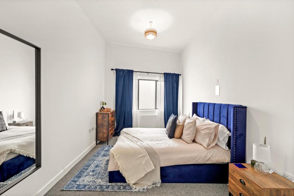 伦敦Luxury London Canary Wharf 2 bed apt的一间卧室配有一张带蓝色床头板和镜子的床