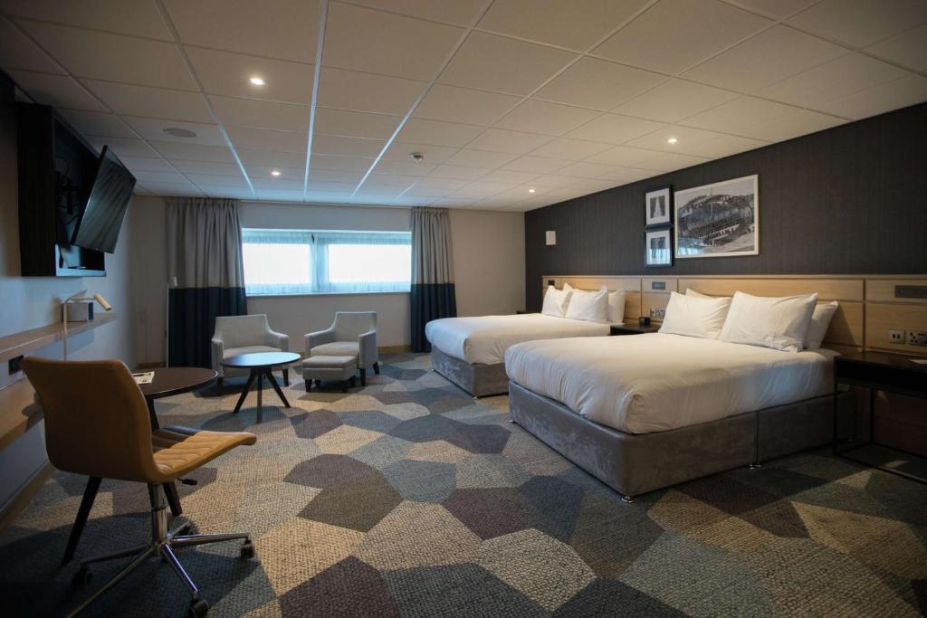 考文垂DoubleTree by Hilton Coventry Building Society Arena的酒店客房带两张床和一张桌子以及椅子。