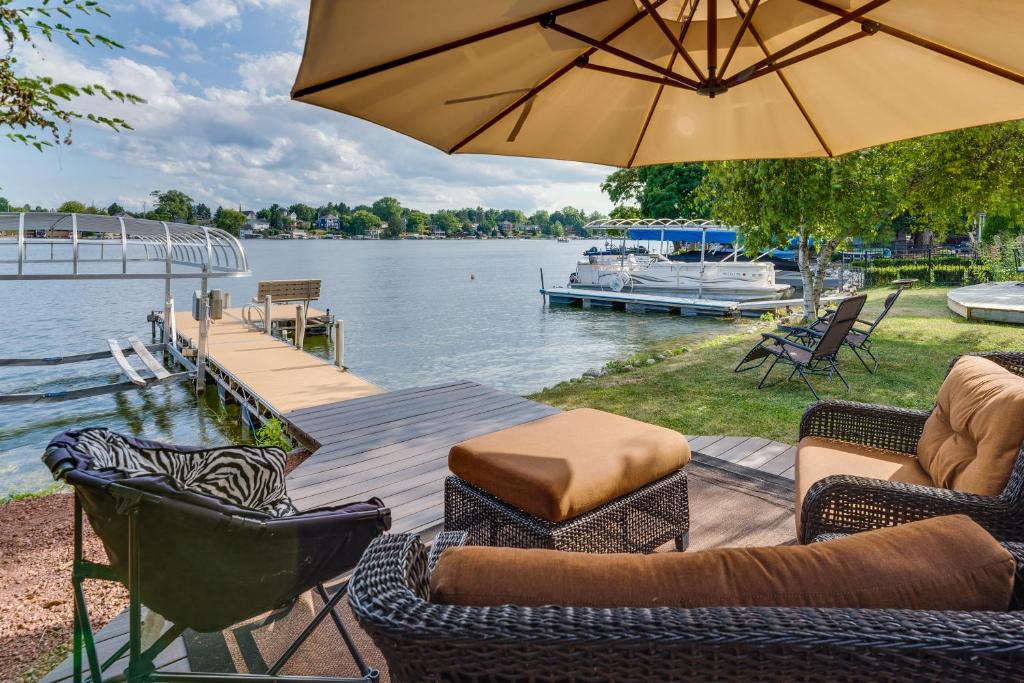 奥康诺摩沃Okauchee Lake Vacation Rental with Boat Dock!的一个带椅子和遮阳伞的临水露台