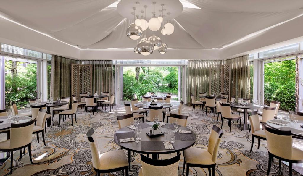 慕尼黑希尔顿慕尼黑公园酒店的用餐室设有桌椅和窗户。