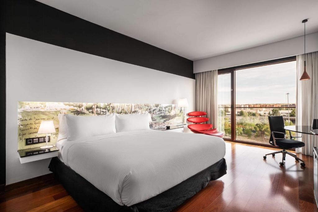 马德里希尔顿马德里机场酒店的一间卧室设有一张大床和一个大窗户