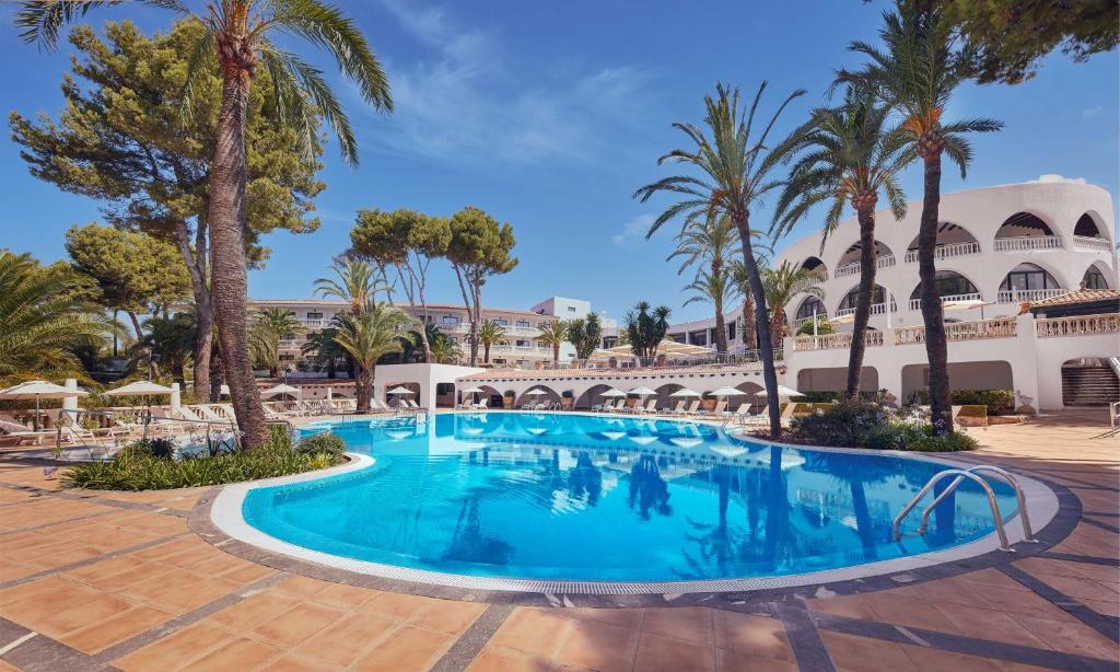帕格拉Hilton Mallorca Galatzo的棕榈树度假村庭院内的游泳池