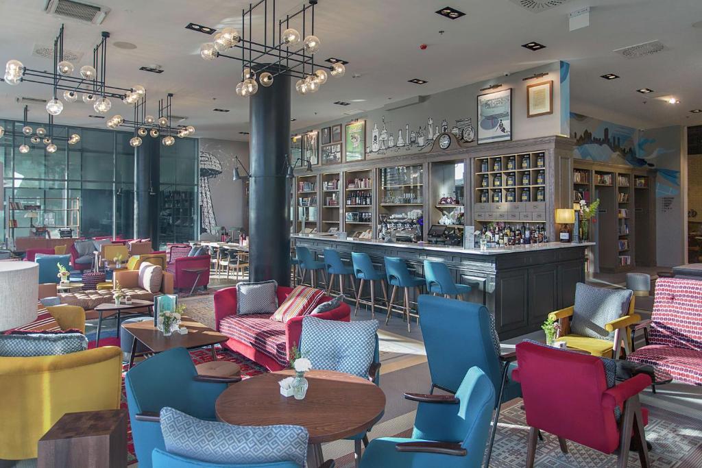 萨格勒布Canopy by Hilton Zagreb City Centre的一间设有五颜六色椅子的餐厅和一间酒吧