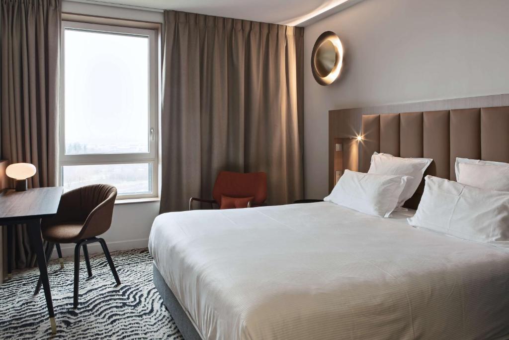 圣普列斯特DoubleTree by Hilton Lyon Eurexpo的酒店客房设有一张大床和一张书桌。