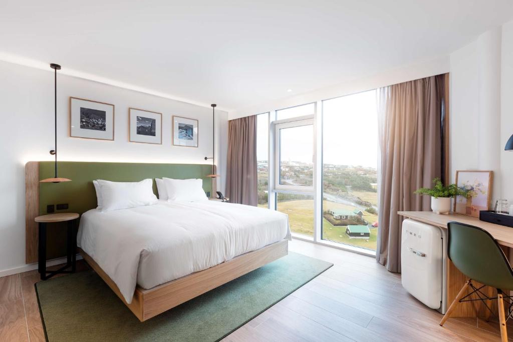 托尔斯港Hilton Garden Inn Faroe Islands的一间卧室配有一张床、一张书桌和一个大窗户