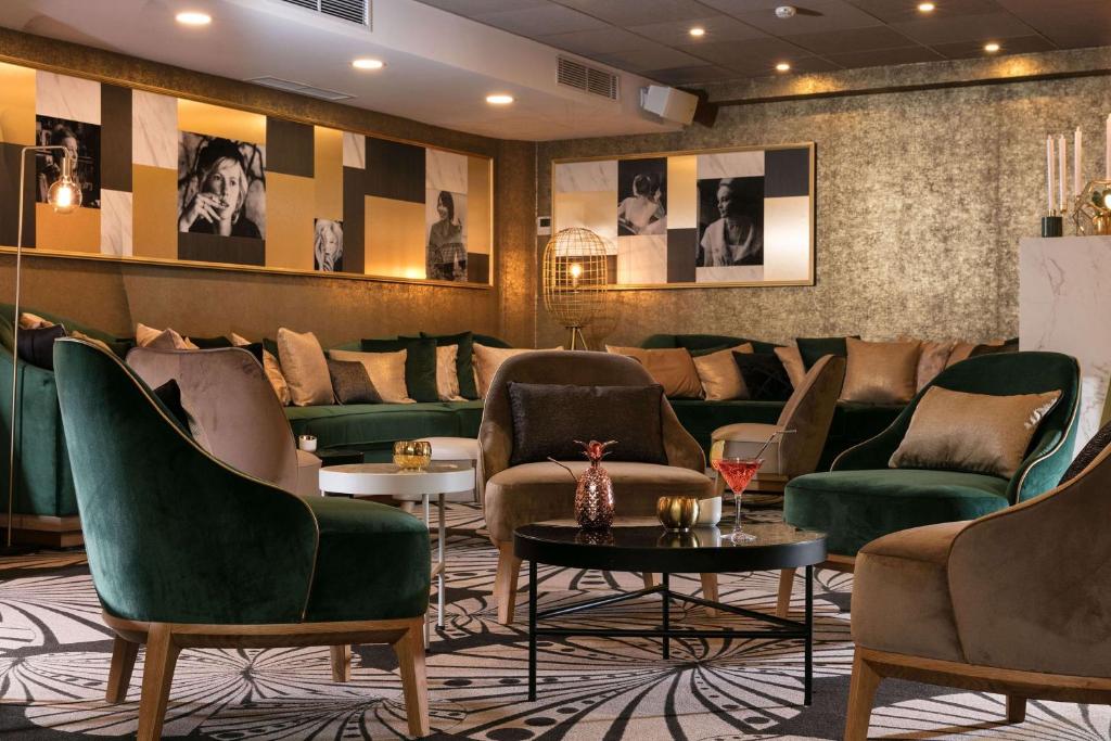巴黎尼皮斯巴黎希尔顿Curio Collection酒店的一间设有绿色椅子和桌子的等候室