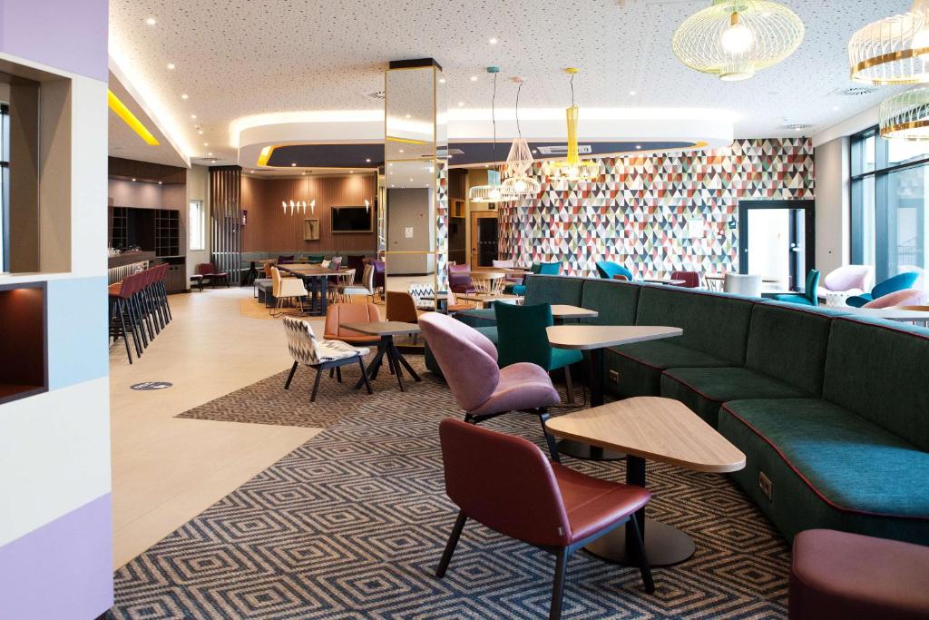 哈尔伯格摩斯Hampton by Hilton Munich Airport South的餐厅设有绿色的沙发和桌椅