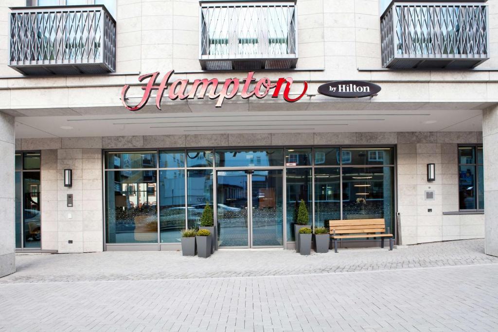 多特蒙德多特蒙德凤凰湖汉普顿酒店 的前面的商店,前面有长凳