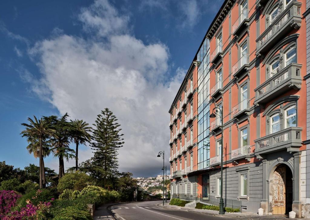 那不勒斯The Britannique Hotel Naples, Curio Collection By Hilton的棕榈树街道边的建筑