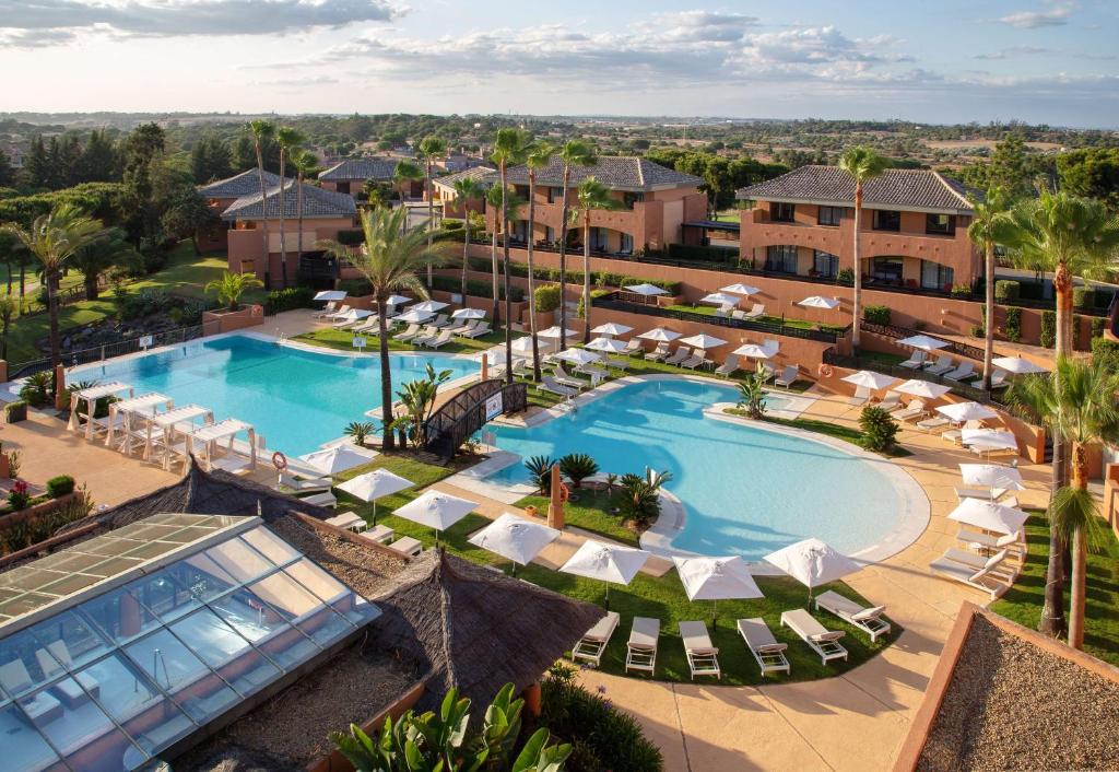 伊斯兰蒂拉DoubleTree by Hilton Islantilla Beach Golf Resort的享有带躺椅的度假游泳池的空中景致