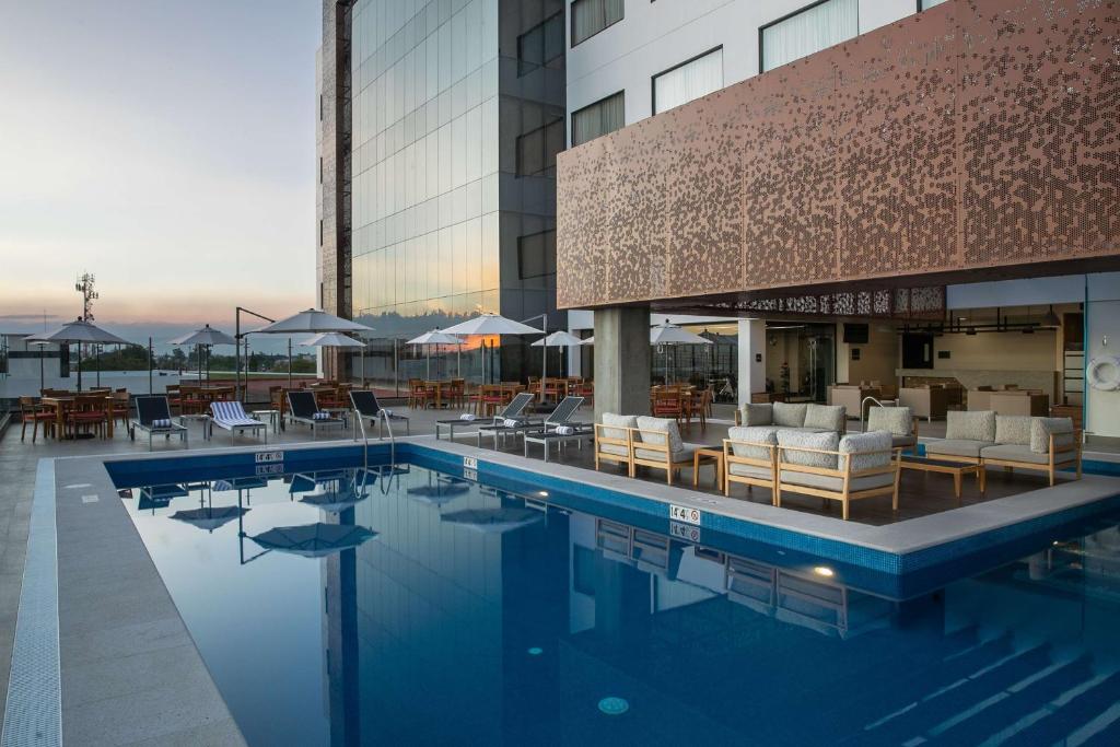 塞拉亚Doubletree By Hilton Celaya的一座带桌椅的游泳池以及一座建筑
