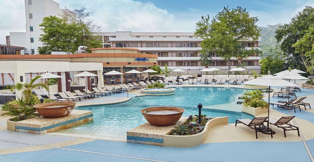 西班牙港特立尼达希尔顿会议酒店 的一张酒店游泳池的图片,里面摆放着椅子和遮阳伞