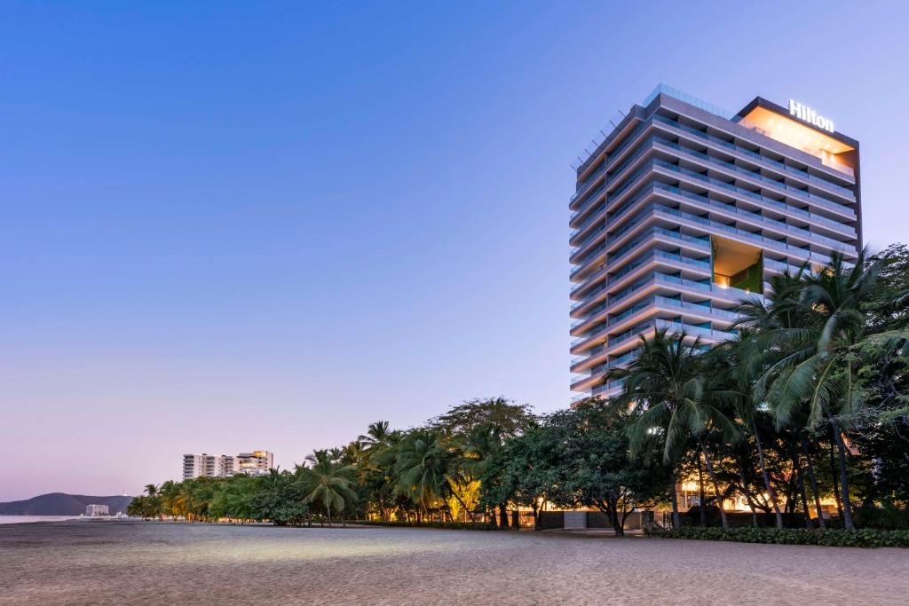 圣玛尔塔Hilton Santa Marta的一座高大的建筑,前面有棕榈树