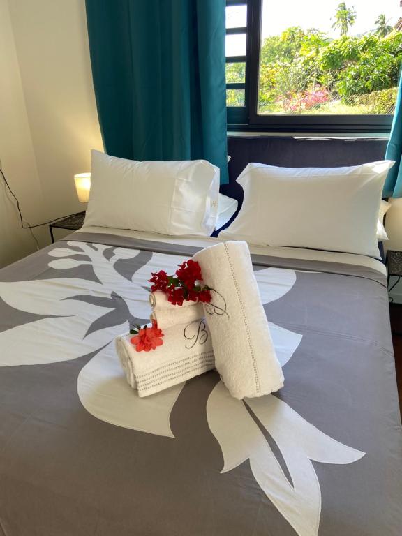帕皮提Manaeva L6的酒店客房,配有两张带毛巾和鲜花的床