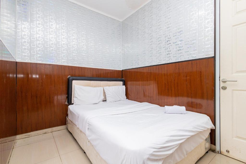 当格浪Alfa Guesthouse Serpong Mitra RedDoorz的卧室配有白色的床和木墙