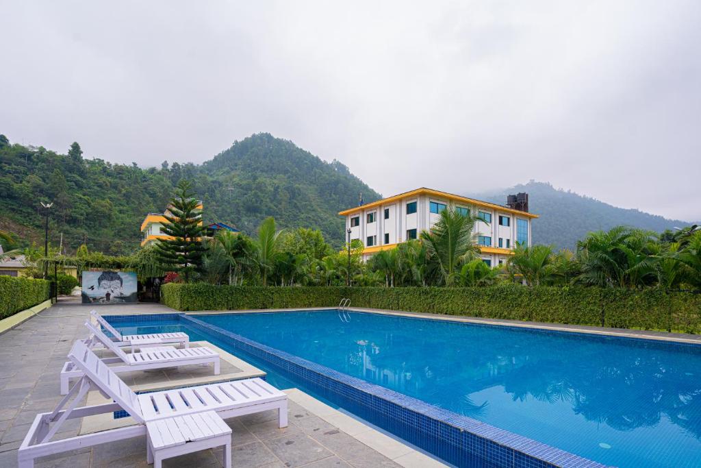 MakaisingSiddhartha Riverside Resort, Chumlingtar的一座带两把白色椅子的游泳池和一座建筑