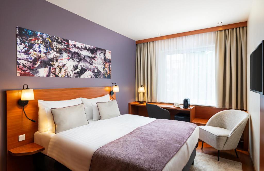 萨尔茨堡Leonardo Hotel Salzburg City Center的配有一张床和一张书桌的酒店客房