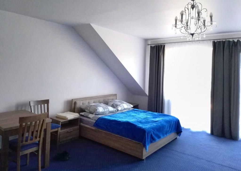 PrzytykArkadia的一间卧室配有一张床、一张桌子和一个吊灯。