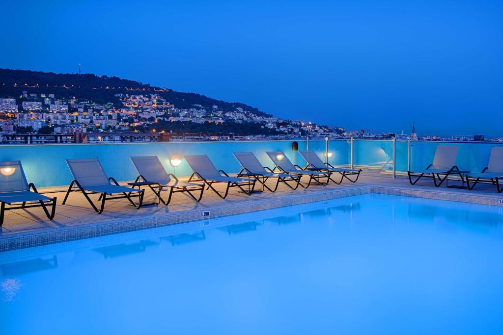 尼斯NH尼斯酒店的夜晚一排椅子和一个游泳池