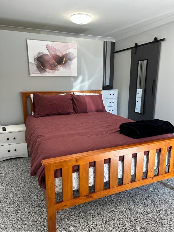 ClermontClermont Guest House的一间卧室配有一张铺有红色床单的木床。