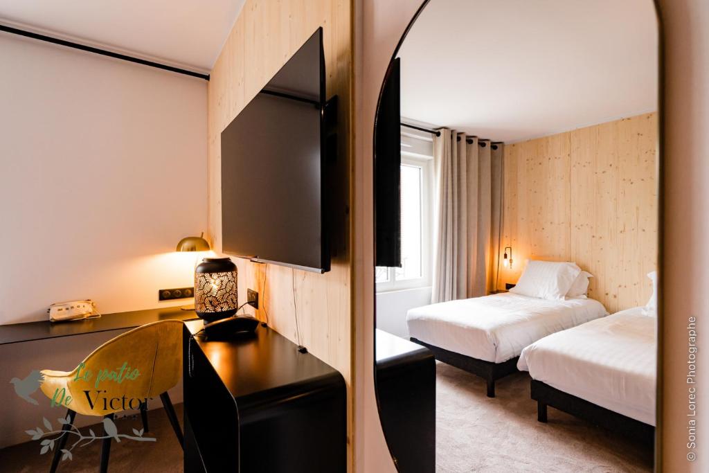 洛里昂Hôtel Le Patio de Victor, Lorient的酒店客房设有一间带两张床和一张书桌的卧室