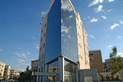 安曼Galaxy Amman Hotel的一座高大的玻璃建筑,映衬着天空