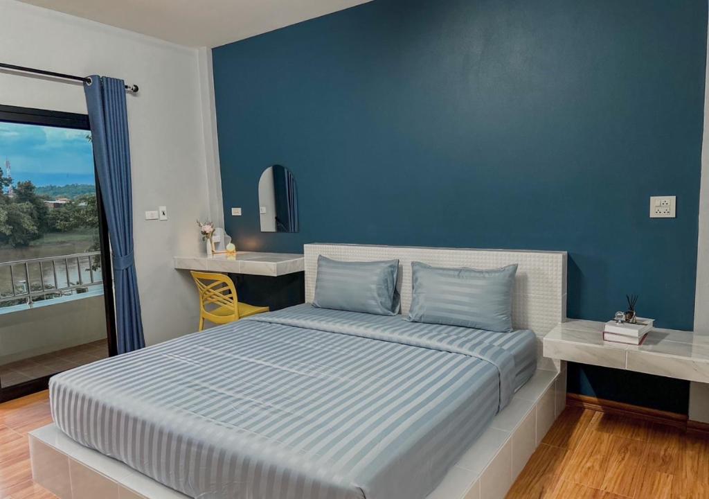 程逸府โรงแรมดีดีธาราอิน - DD tara inn的一间卧室配有一张蓝色墙壁的床